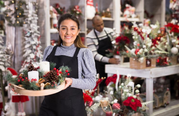 holiday marketing and promotions - small business owner holding christmas decorations in holiday store